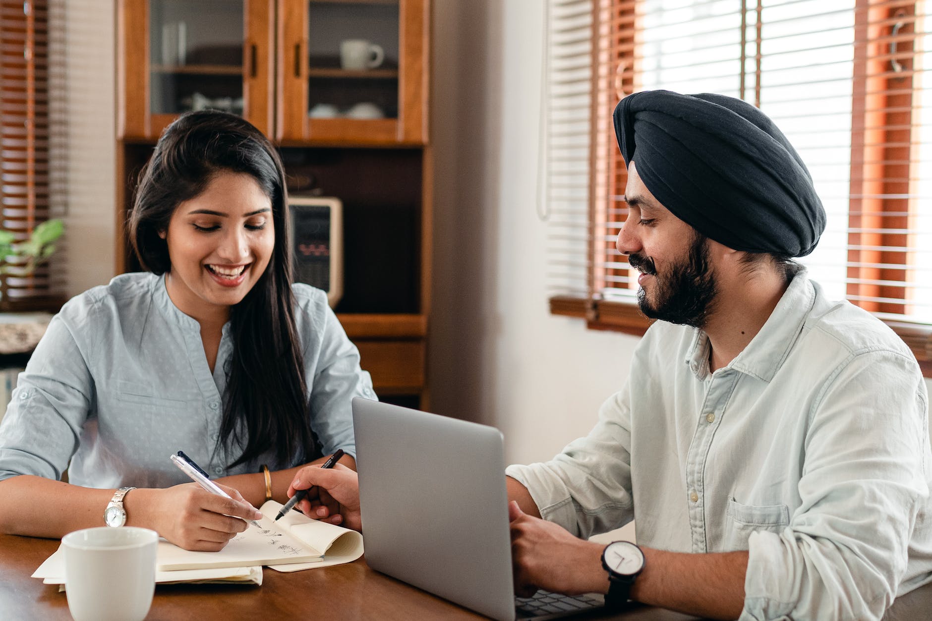 happy indian couple using laptop while doing homework together